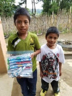 Two young boys with a bag of toothbrushes 